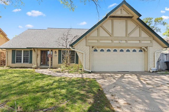 tudor home featuring a garage, a front yard, roof with shingles, brick siding, and concrete driveway