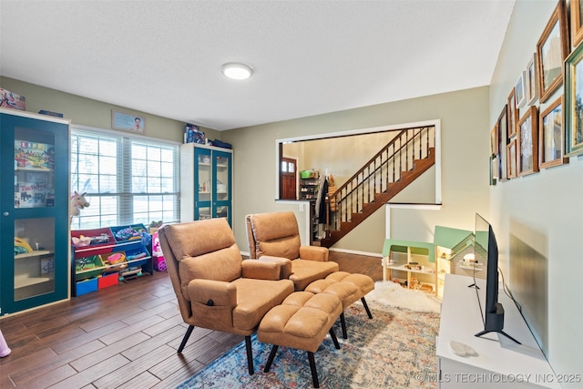 sitting room with wood finished floors and stairway