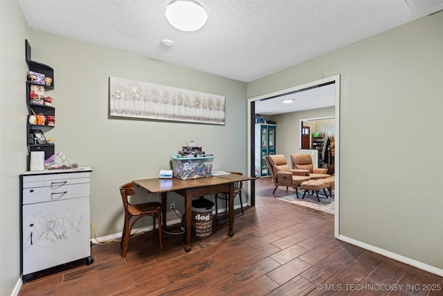 dining space featuring a textured ceiling, baseboards, and wood finished floors