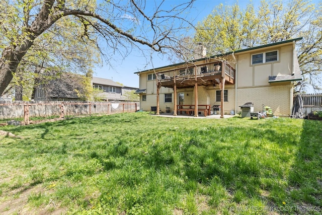 rear view of property with brick siding, a fenced backyard, a yard, and a deck