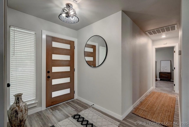 foyer featuring baseboards, visible vents, and wood finished floors