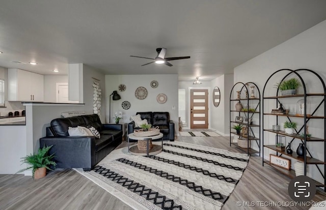living area with baseboards, ceiling fan, and light wood-style flooring