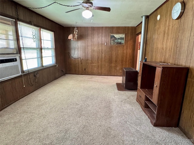 unfurnished room featuring light colored carpet, wood walls, a ceiling fan, and cooling unit
