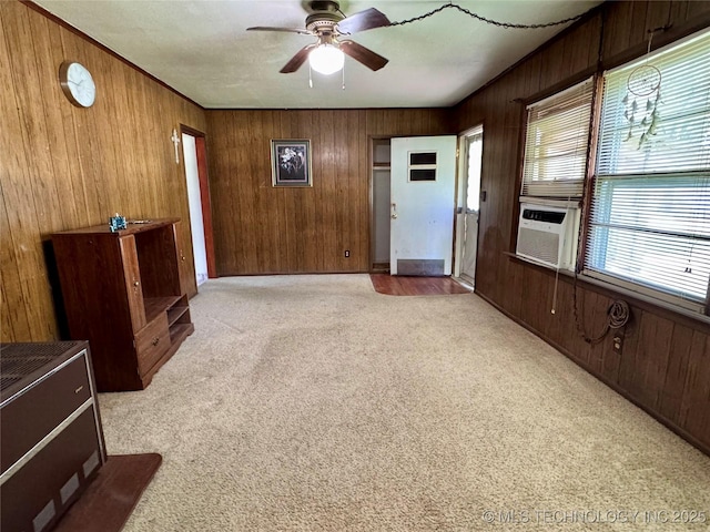 unfurnished living room featuring wood walls, a ceiling fan, carpet, and cooling unit