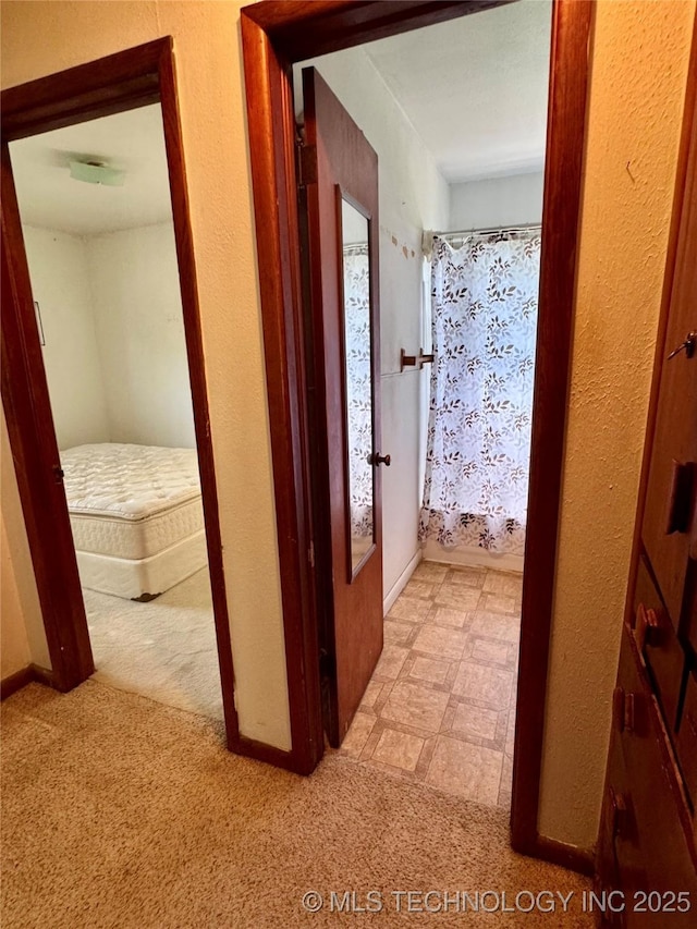 corridor featuring light carpet and baseboards