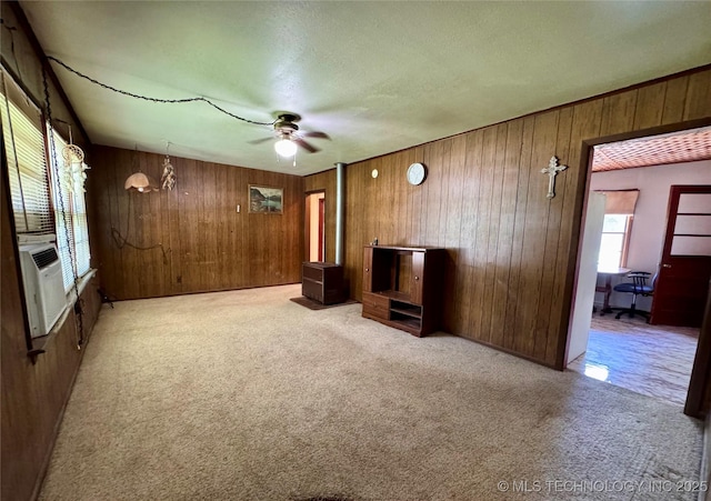 unfurnished living room with wooden walls, carpet flooring, ceiling fan, and cooling unit