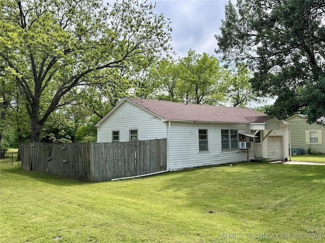rear view of house with an attached garage, cooling unit, and a shingled roof