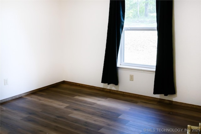 unfurnished room with baseboards and dark wood finished floors