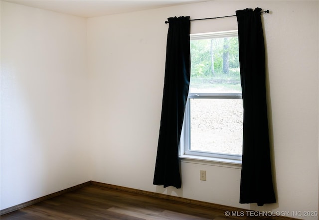unfurnished room with baseboards and dark wood-style floors