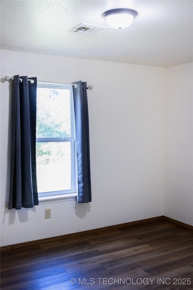 unfurnished room featuring plenty of natural light, wood finished floors, and visible vents