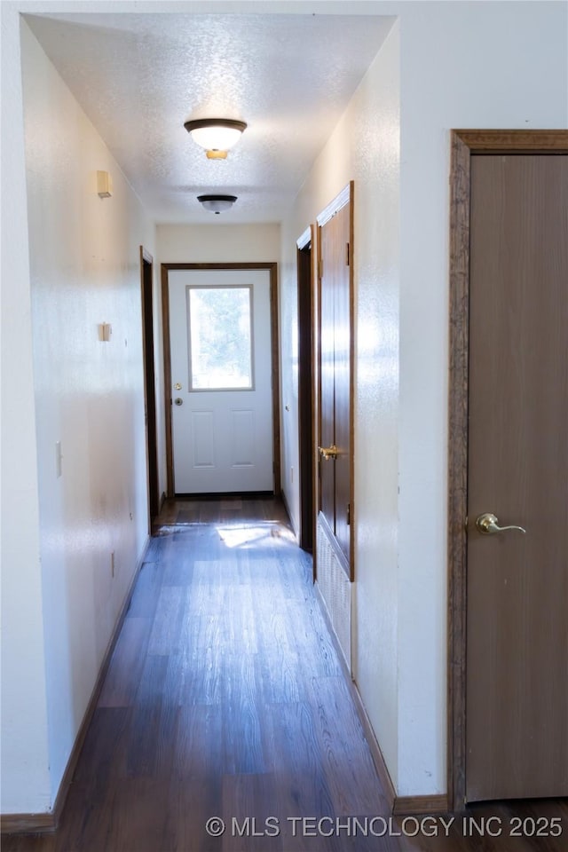hall with baseboards, a textured ceiling, and wood finished floors