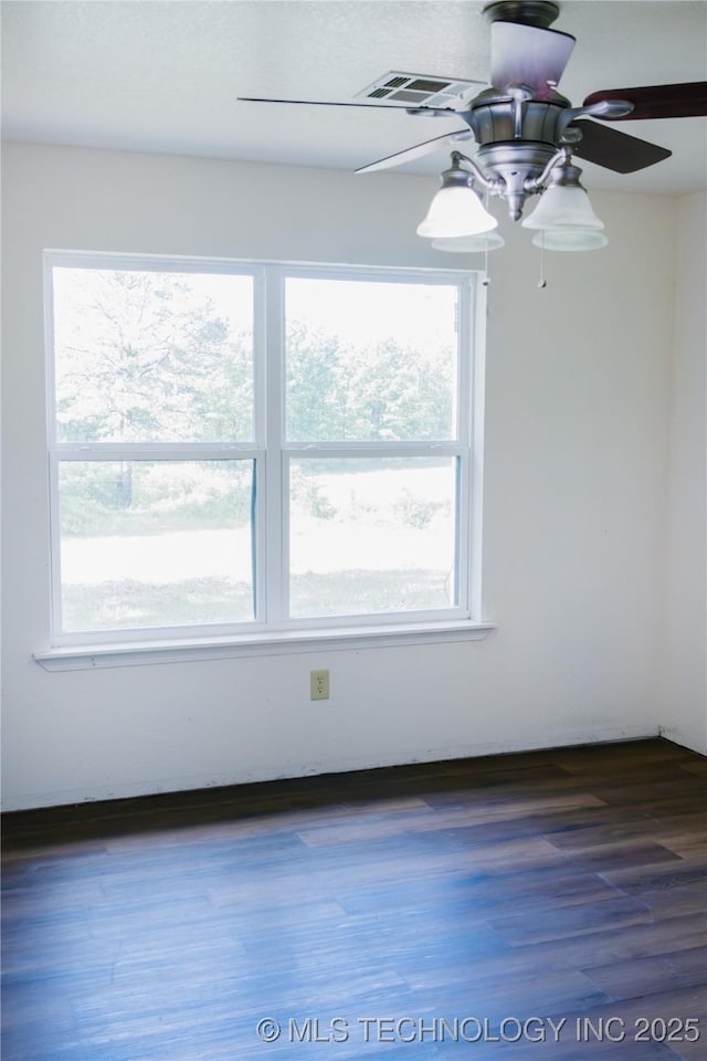 empty room featuring a ceiling fan, visible vents, and wood finished floors