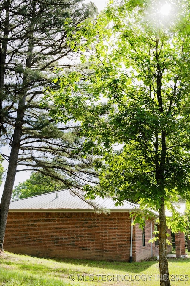view of property exterior featuring brick siding and metal roof
