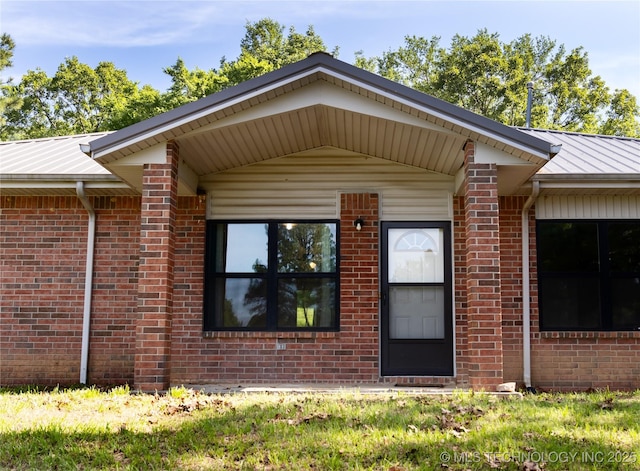 property entrance featuring brick siding, a standing seam roof, and metal roof