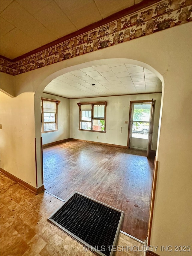 unfurnished room with arched walkways, baseboards, visible vents, and a healthy amount of sunlight