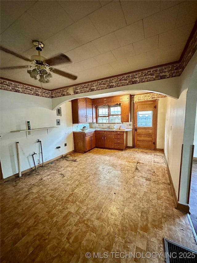 interior space with brown cabinetry, arched walkways, a ceiling fan, and visible vents