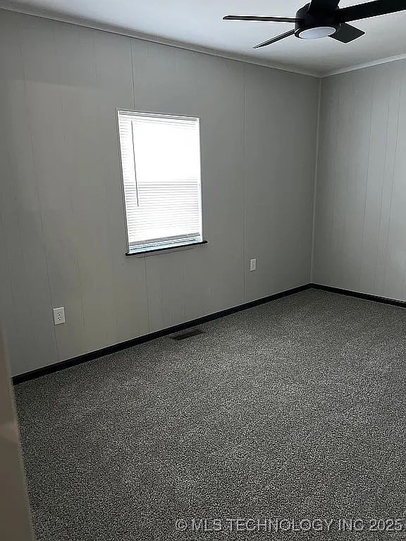 empty room featuring baseboards, a ceiling fan, speckled floor, and visible vents