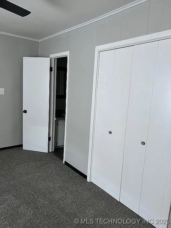 unfurnished bedroom with baseboards, ornamental molding, and a closet