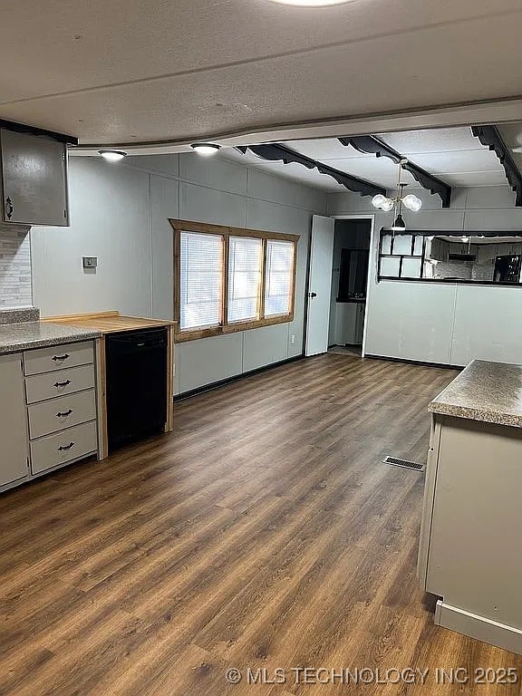 kitchen with black dishwasher, visible vents, beam ceiling, and dark wood-style floors