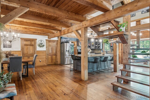 interior space with a healthy amount of sunlight, a chandelier, beam ceiling, and wainscoting