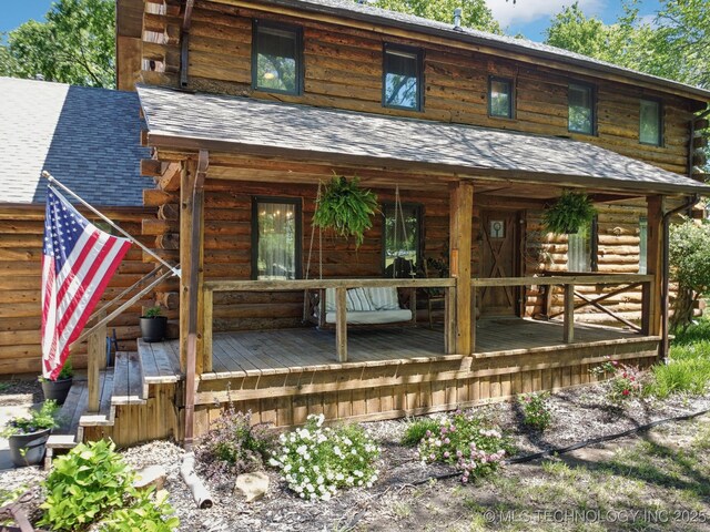 exterior space featuring a wooden deck and a shingled roof