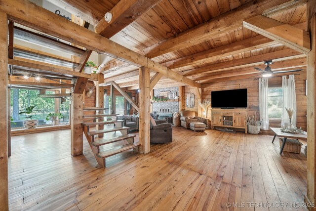 living room featuring beam ceiling, wood-type flooring, plenty of natural light, wooden ceiling, and ceiling fan