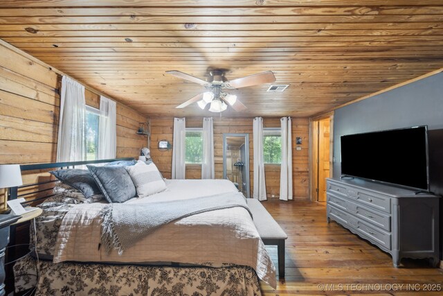 bedroom with hardwood / wood-style floors, multiple windows, wood walls, wood ceiling, and ceiling fan