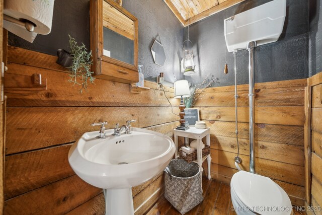 half bathroom featuring wood finished floors, toilet, and a sink