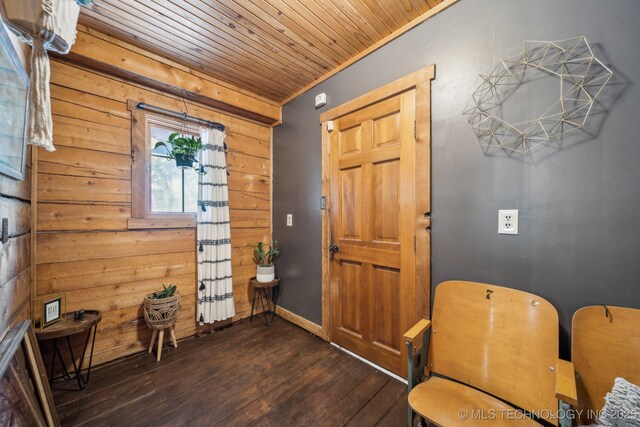entryway with hardwood / wood-style floors, wooden walls, wood ceiling, and baseboards