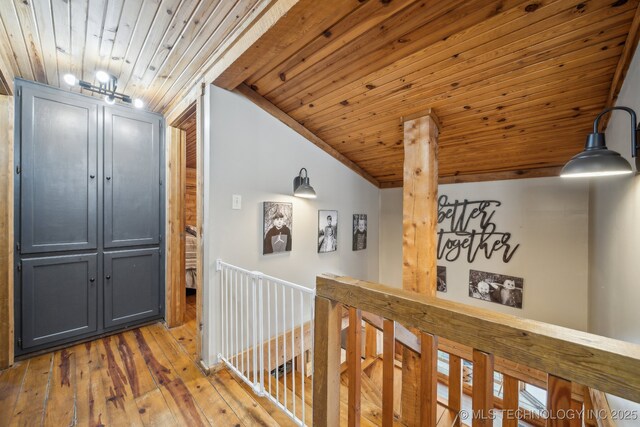corridor with light wood-style floors, wood ceiling, and vaulted ceiling