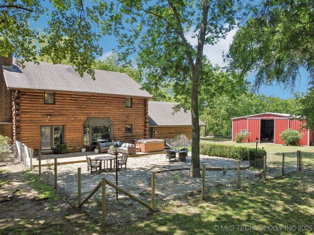view of yard with a hot tub, fence, a pole building, a patio area, and an outdoor structure