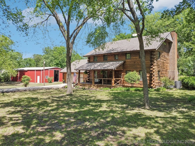 rear view of property featuring a yard, a chimney, log exterior, and central AC
