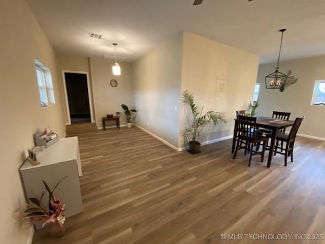 dining space featuring wood finished floors, baseboards, plenty of natural light, and a chandelier