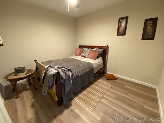 bedroom featuring wood finished floors, baseboards, and ceiling fan