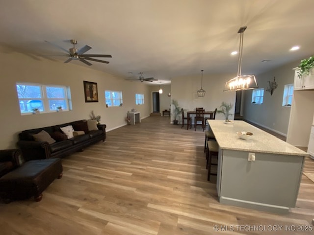 living room with ceiling fan, light wood-style floors, healthy amount of natural light, recessed lighting, and baseboards