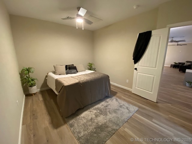 bedroom featuring wood finished floors, baseboards, and a ceiling fan
