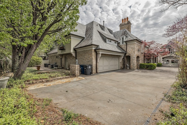 2119 E 30th Pl, Tulsa, OK 74114 - view of side of property with stone siding, concrete driveway, stucco siding, and a chimney