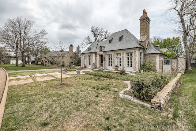 2119 E 30th Pl, Tulsa, OK 74114 - back of house with stone siding, a yard, a chimney, and a patio