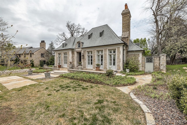 2119 E 30th Pl, Tulsa, OK 74114 - rear view of house with a lawn, stone siding, french doors, and a chimney