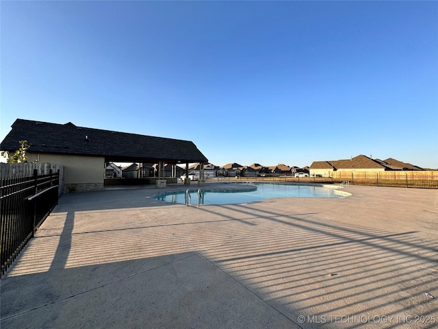 community pool with a patio and fence