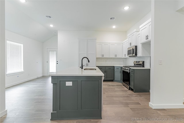 10914 S 272nd E Ave, Coweta, OK 74429 - kitchen featuring stainless steel appliances, tasteful backsplash, an island with sink, vaulted ceiling, and light wood-style flooring