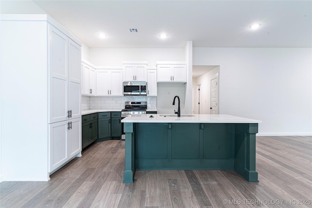 10914 S 272nd E Ave, Coweta, OK 74429 - kitchen with stainless steel appliances, light wood-type flooring, decorative backsplash, a center island with sink, and light countertops