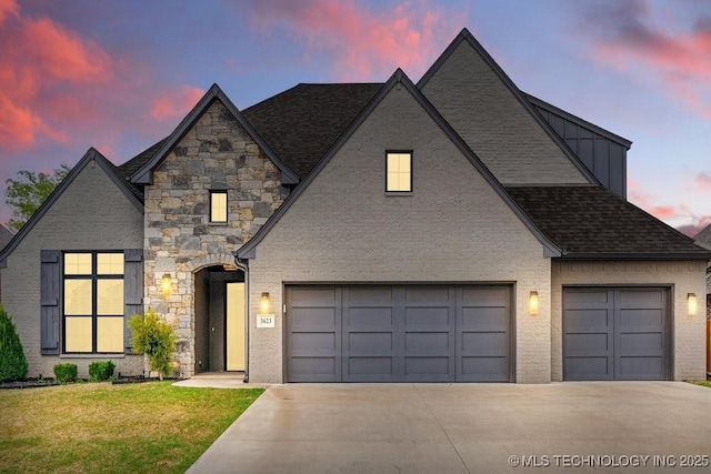 view of front of property with driveway, a front yard, stone siding, and a garage