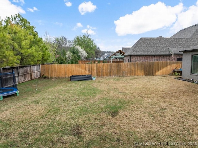view of yard with a trampoline and a fenced backyard
