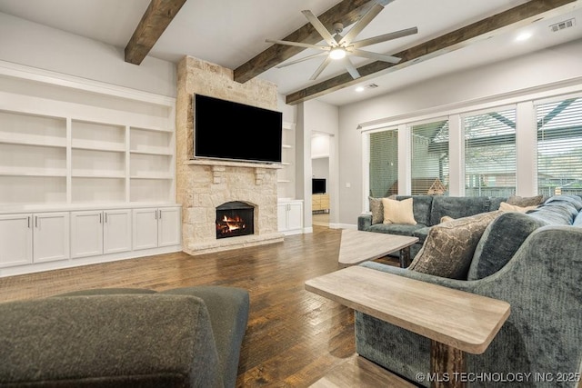 living area with wood finished floors, visible vents, a fireplace, ceiling fan, and beamed ceiling