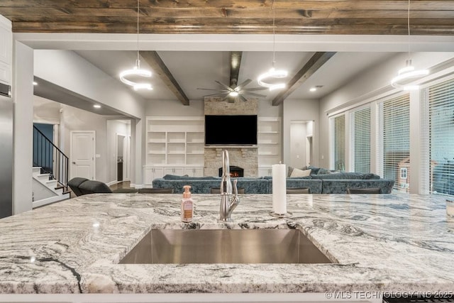 kitchen featuring a fireplace, light stone countertops, open floor plan, and a sink