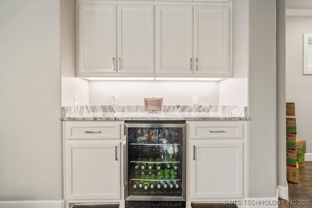 bar featuring wine cooler, a bar, and baseboards