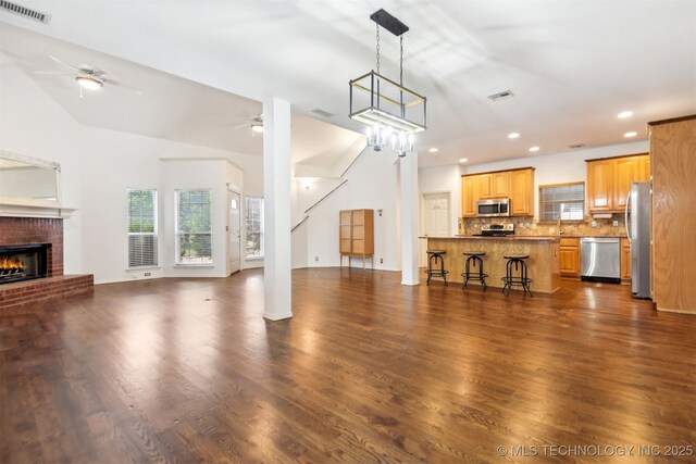 unfurnished living room featuring ceiling fan, a brick fireplace, dark wood-type flooring, recessed lighting, and a sink
