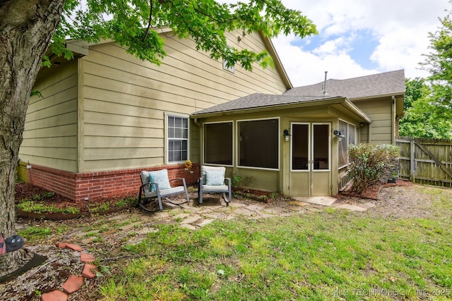 back of property with a shingled roof and a sunroom