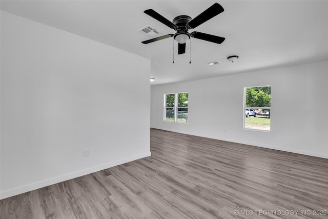 unfurnished room with ceiling fan, baseboards, visible vents, and wood finished floors